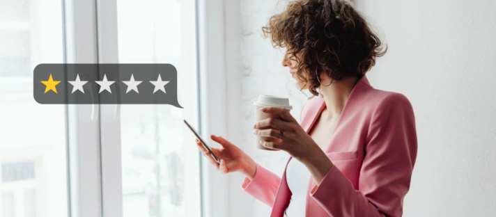 Woman looking at her phone with a one-star bad review, illustrating the challenge of handling negative feedback for businesses.