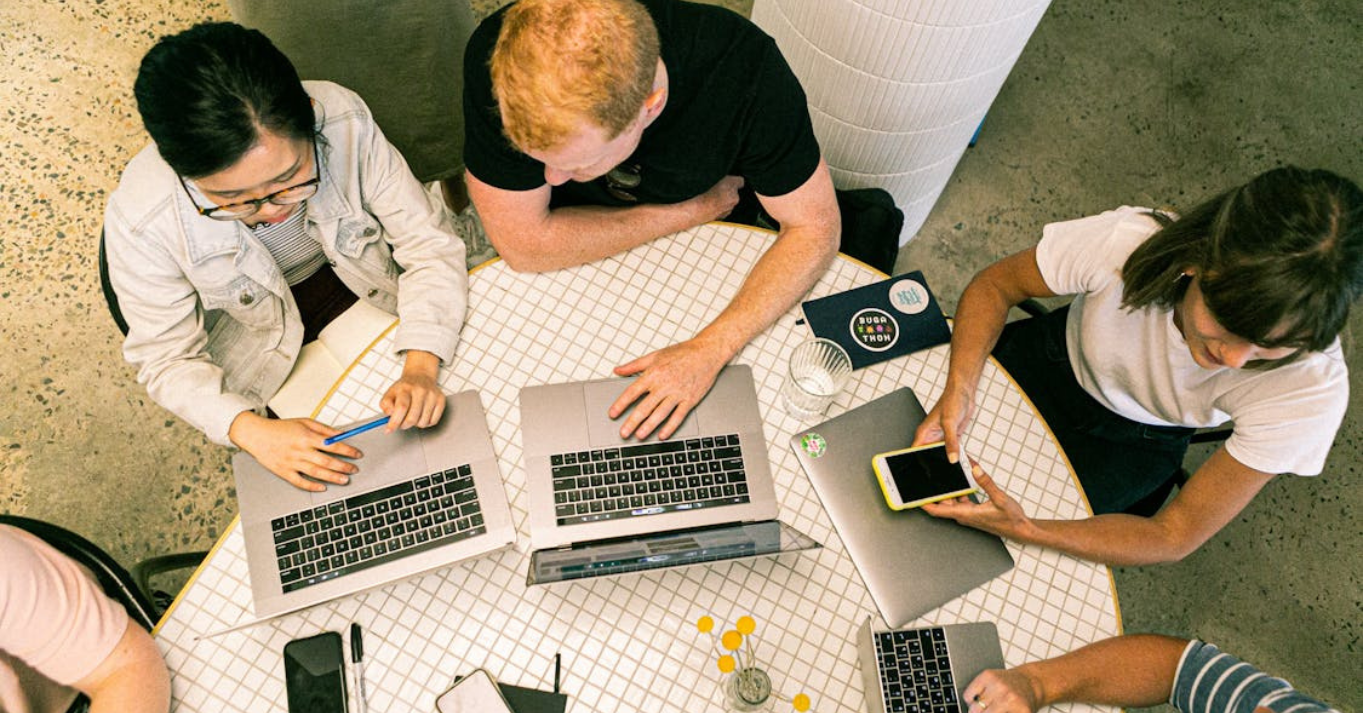 A marketing team discussing effective marketing strategies for plastic surgeons at a table with laptops and smartphones.