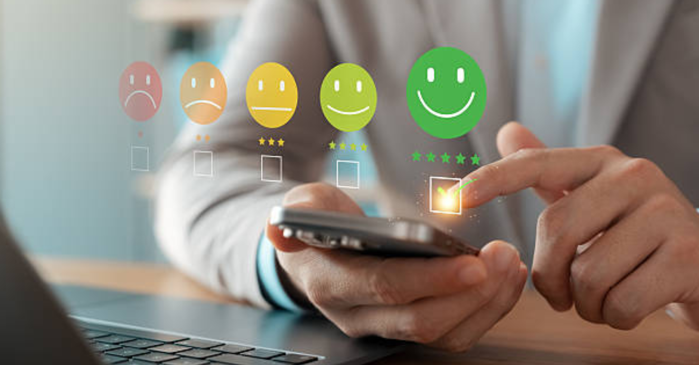 Hand selecting a five-star happy face review on a mobile phone screen, illustrating excellent online reputation for your clinic and patient satisfaction management.